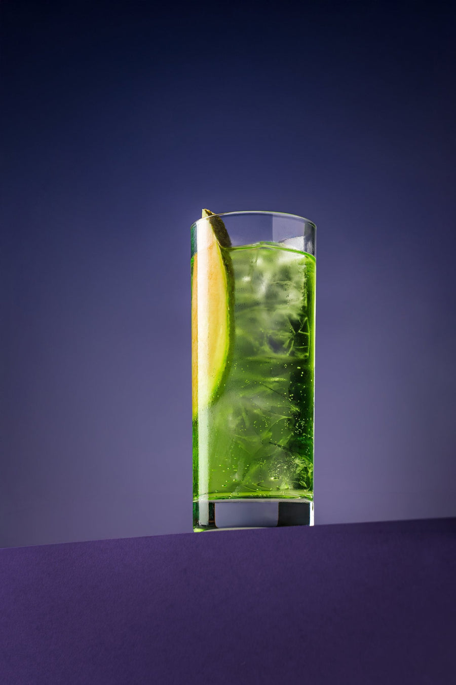 Melon Highball in a highball glass with a melon slice, on purple