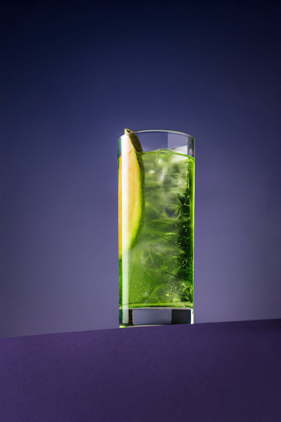 Melon Highball in a highball glass with a melon slice, on purple